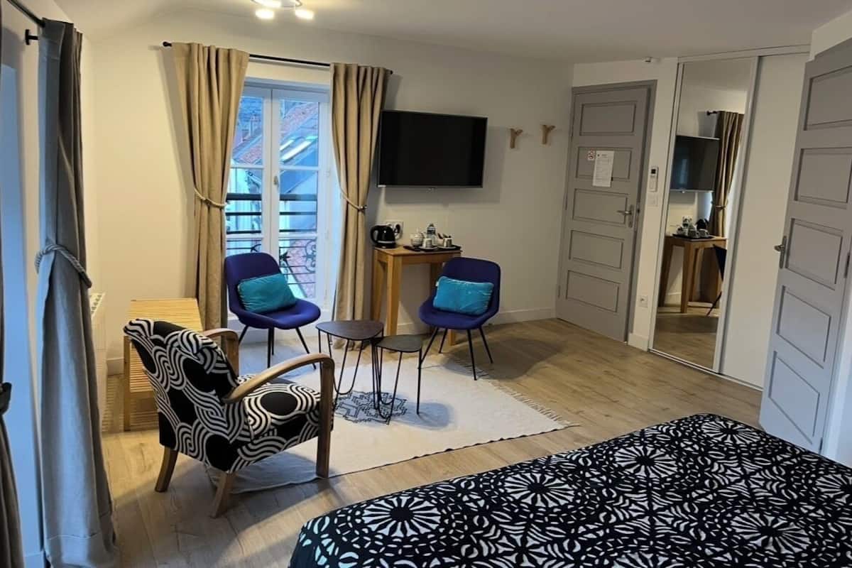 Una camera con un letto, due poltrone, una televisione e un tavolino con una macchina per il caffè.