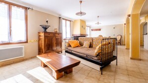Een woonkamer met een bank, een houten tafel, een radiator en een raam met gordijnen.