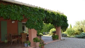 A building with a covered patio, outdoor seating, and a gravel driveway. - Magnificent Provençal villa in a quiet private domain (Tourtour)