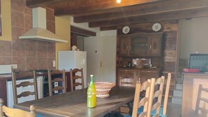Un coin repas avec une table en bois, des chaises dotées de coussins bleus, une bouteille et un panier tressé.