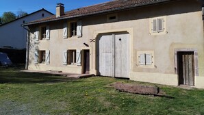 Un bâtiment à deux étages, doté d’un toit en tuiles, d’une grande porte de garage et de nombreuses fenêtres équipées de volets.
