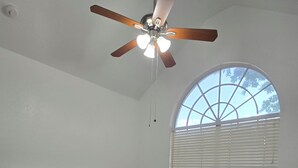 A bedroom with a bed, a ceiling fan, a window with blinds, and a white wall. - Adorable 2-bedroom house with AC in charming Lewisville (Lewisville)