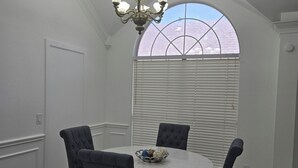 A dining area with a round table, four chairs, a chandelier, and a window with blinds. - Adorable 2-bedroom house with AC in charming Lewisville (Lewisville)