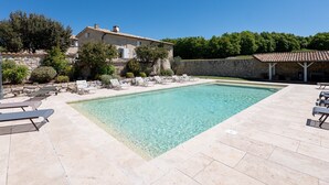 A swimming pool with lounge chairs, a stone house, and a stone wall. - Holiday Home “Bastide de Marius” with Shared Pool, Terrace, and Wi-Fi (Redortiers)