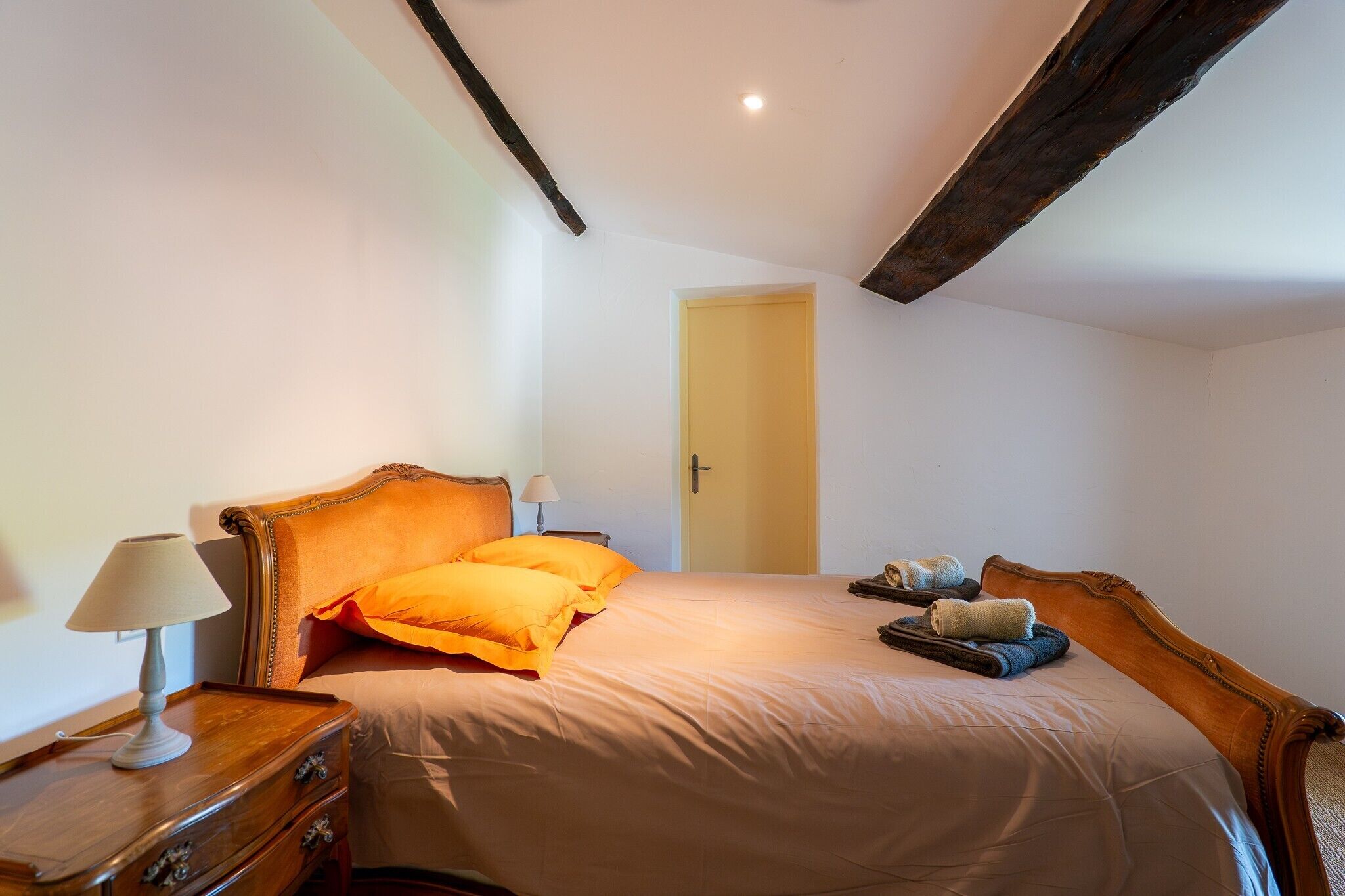 A bedroom with a bed, bedside tables, a lamp, and a door.
