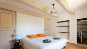 A bedroom with a bed, two pillows, a bedside table with a lamp, and a hanging light fixture. - Holiday Home “Bastide de Marius” with Shared Pool, Terrace, and Wi-Fi (Redortiers)