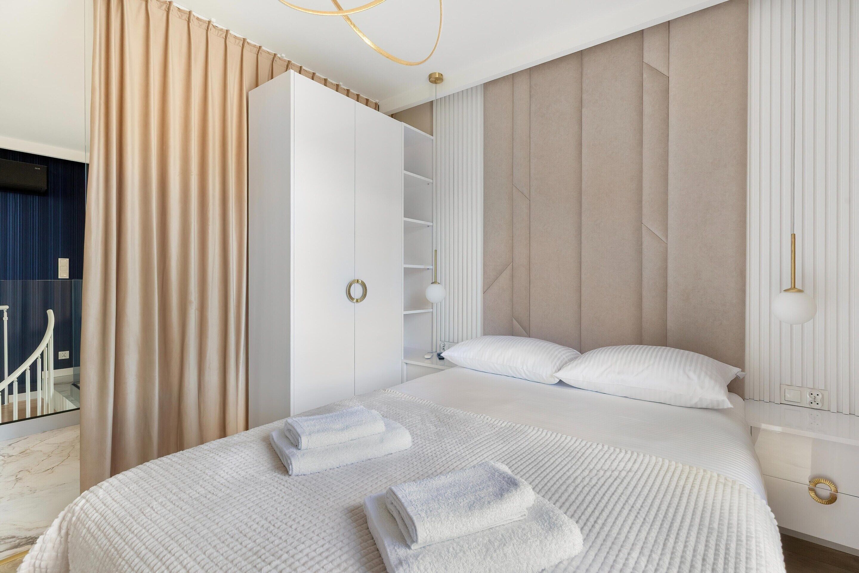 A modern hotel room with a large bed, a wardrobe, and a mirror.