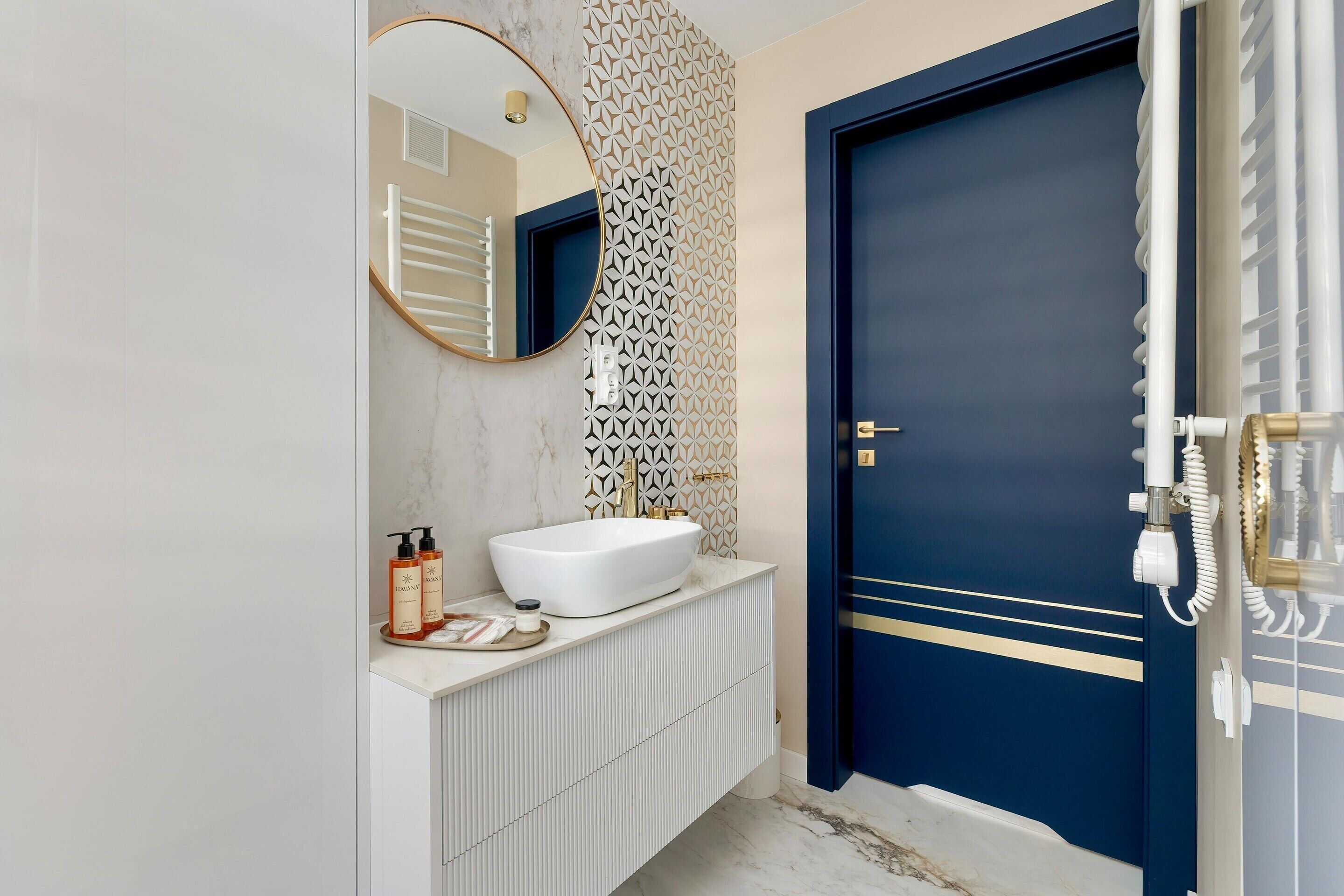 A bathroom with a white sink, a mirror, a towel rack, and a blue door.