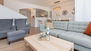 Ein modernes Wohnzimmer mit einer grauen Couch, einer hellgrünen Couch und einem Couchtisch aus Holz mit einem Modellschiff.