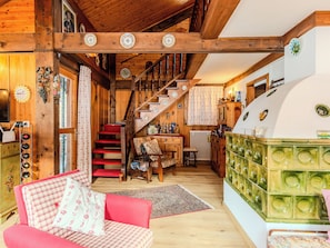 Interior acogedor de una cabaña con una escalera de madera, un comedor y una cocina con salpicadero de azulejos verdes.