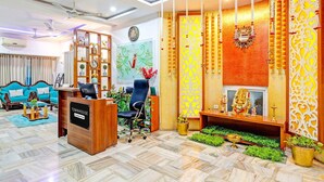 A modern reception area with a desk, chairs, and a decorative wall with hanging ornaments. - Suite Vijaya Residency (Visakhapatnam)