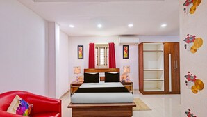 A modern bedroom with a bed, a red chair, a wardrobe, and a decorative wall. - Suite Vijaya Residency (Visakhapatnam)