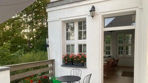 A patio with a table and chairs, a window with flowers, and a door leading inside. - Comfortable House With Access to the Lake, Masuria (Ruciane-Nida)
