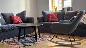 A modern living room with grey sofas, a rocking chair, a small round table, and a patterned rug. - Comfortable House With Access to the Lake, Masuria (Ruciane-Nida)