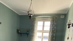 A room with two beds, a window with curtains, a chair, and a wall-mounted light fixture. - Comfortable House With Access to the Lake, Masuria (Ruciane-Nida)