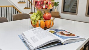A dining table with a fruit basket, a book, and a staircase in the background. - North End 2-Story Penthouse / Prime Location (Boston)
