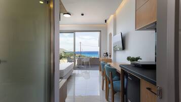 A modern kitchen with a dining area, a large window with a view, and a flat-screen TV mounted on the wall.