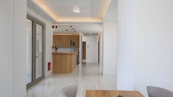 Una moderna hall d'albergo con una reception, un bancone in legno e un'area relax con tavolo e sedie.