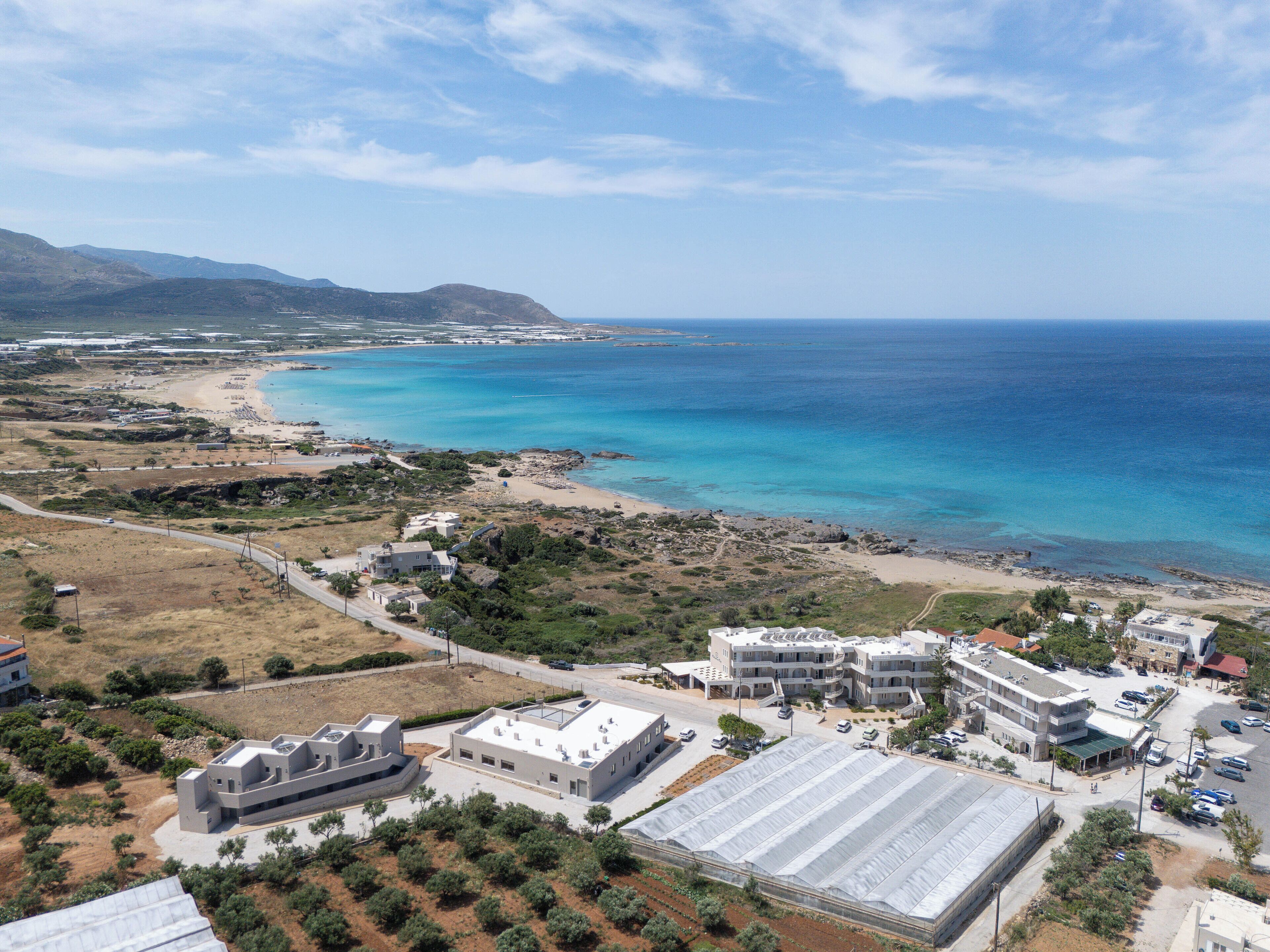 An aerial view of a coastal area with buildings, a road, and a beach.