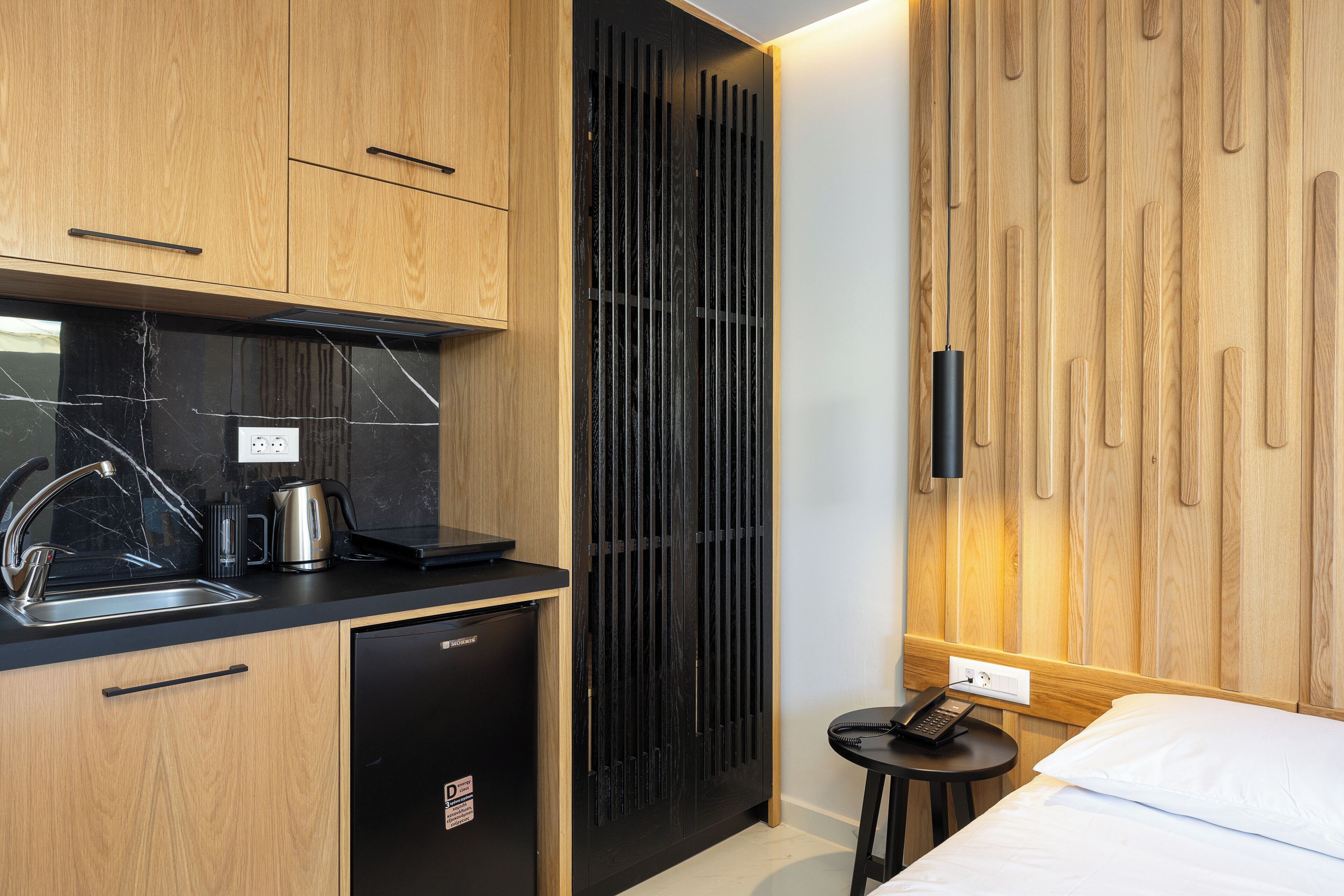 A compact kitchen with a dishwasher, a coffee maker, and a kettle on the counter.