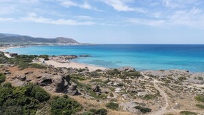 A coastal landscape with a clear sky, rocky terrain, and a beach. - Falasarna Bay Hotel (Kissamos)