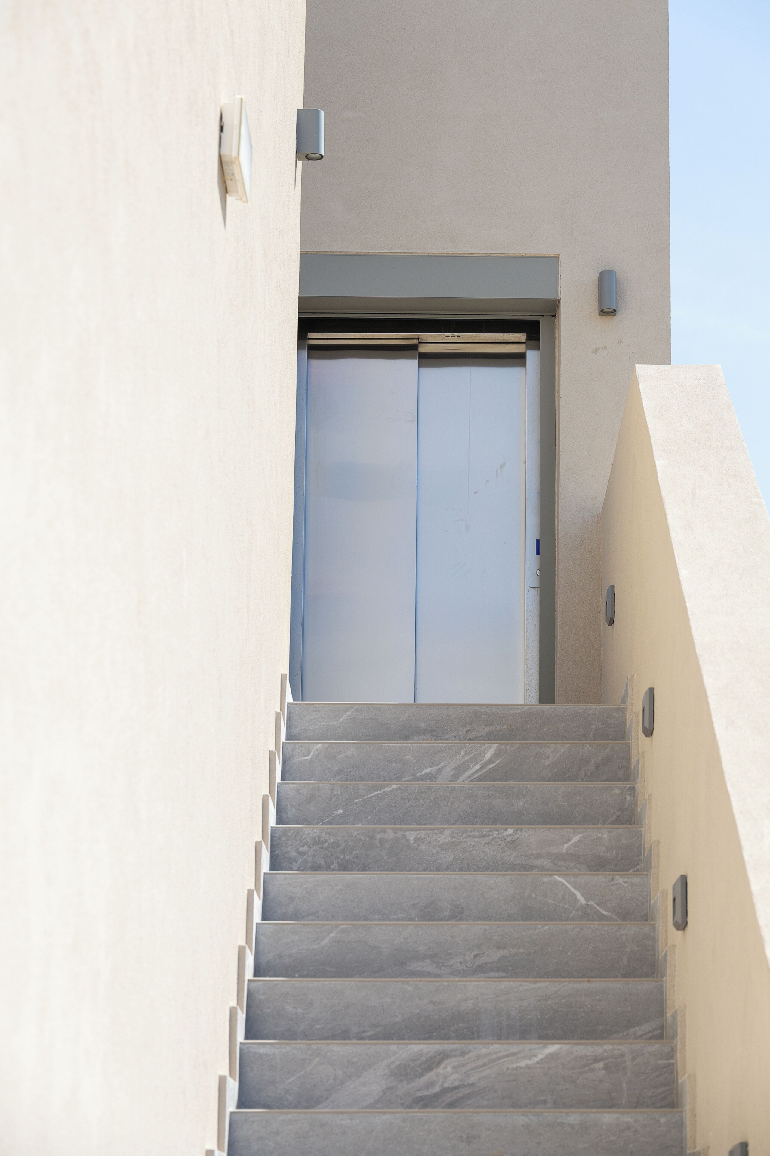 Un escalier menant à une porte, un luminaire et un mur.