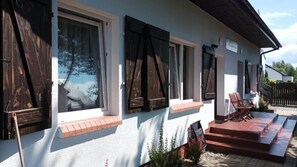 A building with large windows, a covered porch, and a sign indicating a restaurant. - Studio for 3 People, Rowy (Ustka)