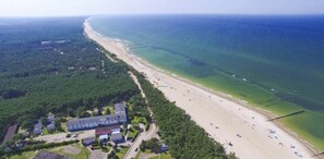An aerial view of a coastal area with a beach, a large building complex, and surrounding greenery. - Studio for 3 People, Rowy (Ustka)