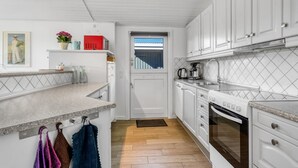 A kitchen with white cabinets, a countertop, a stove, and a window. - "Sofus" - 800m from the sea by Interhome (Væggerløse)