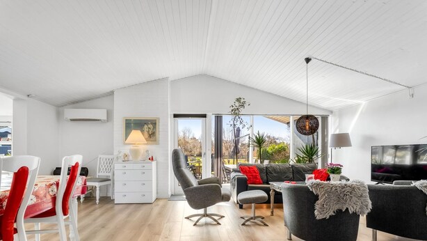 A modern living room with a dining area, a TV, and a large window. - "Sofus" - 800m from the sea by Interhome (Væggerløse)