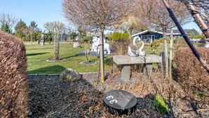A garden with a stone bench, a swan sculpture, and a large white statue in the background. - "Sofus" - 800m from the sea by Interhome (Væggerløse)