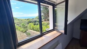 Una habitación con un ventanal grande, un televisor y un banco de madera.