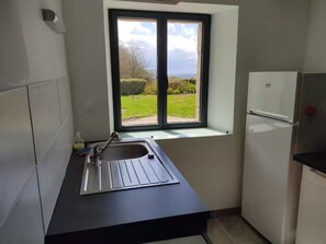 A kitchen with a window, a sink, and a refrigerator. - Renovated Breton house with sea view (Moëlan-sur-Mer)