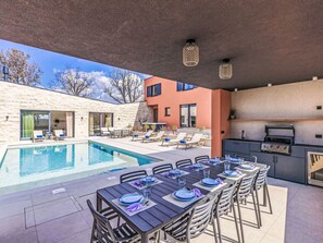 An outdoor pool area with lounge chairs, a dining table set for six, and a barbecue grill. - La Terra by Interhome (Tinjan)