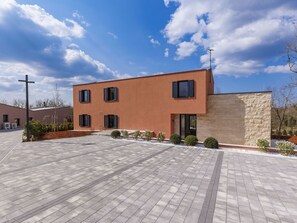 A modern building with a flat roof, a paved courtyard, and a stone wall. - La Terra by Interhome (Tinjan)
