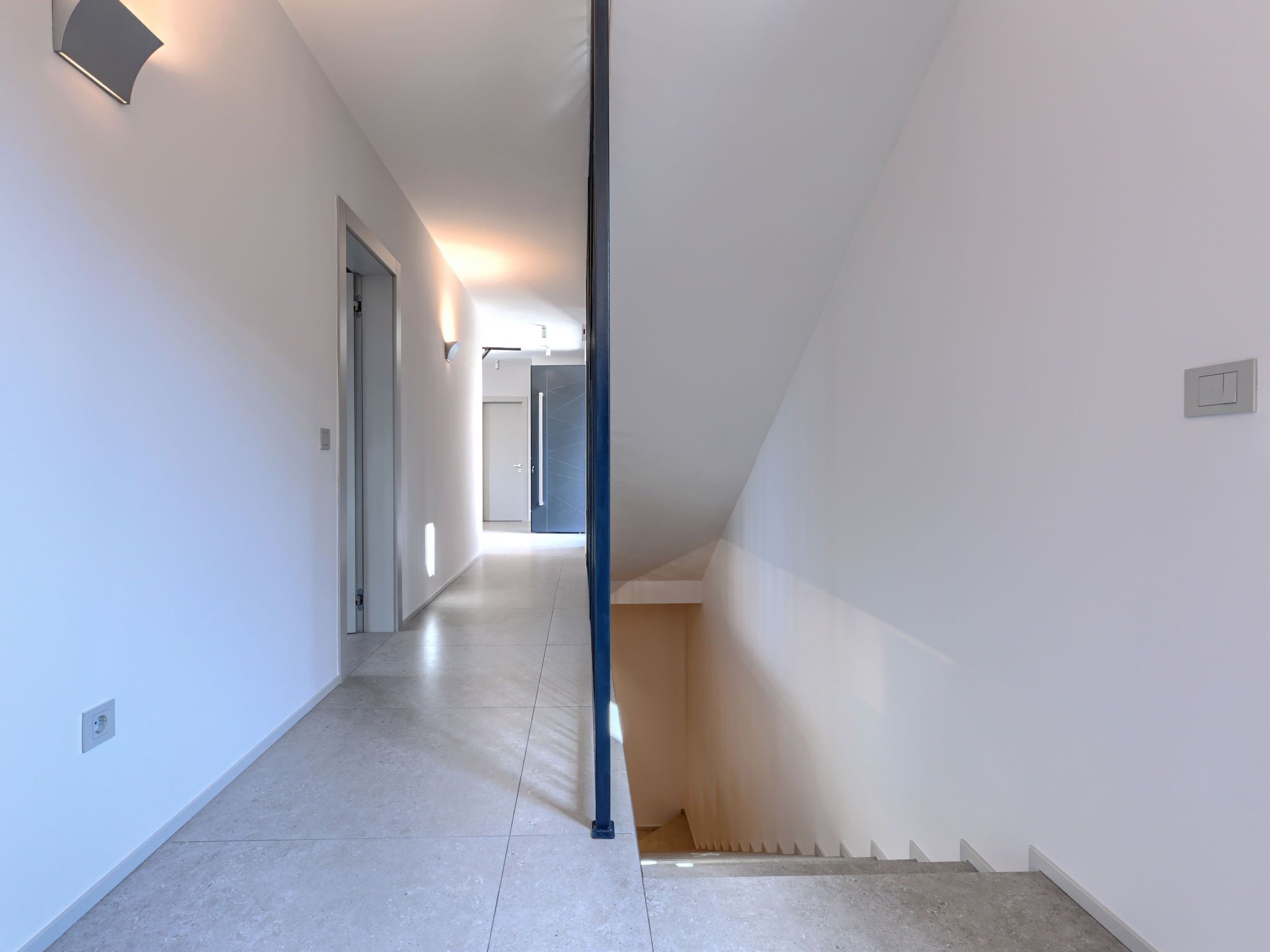 A hallway with a staircase, a door, and a light fixture.