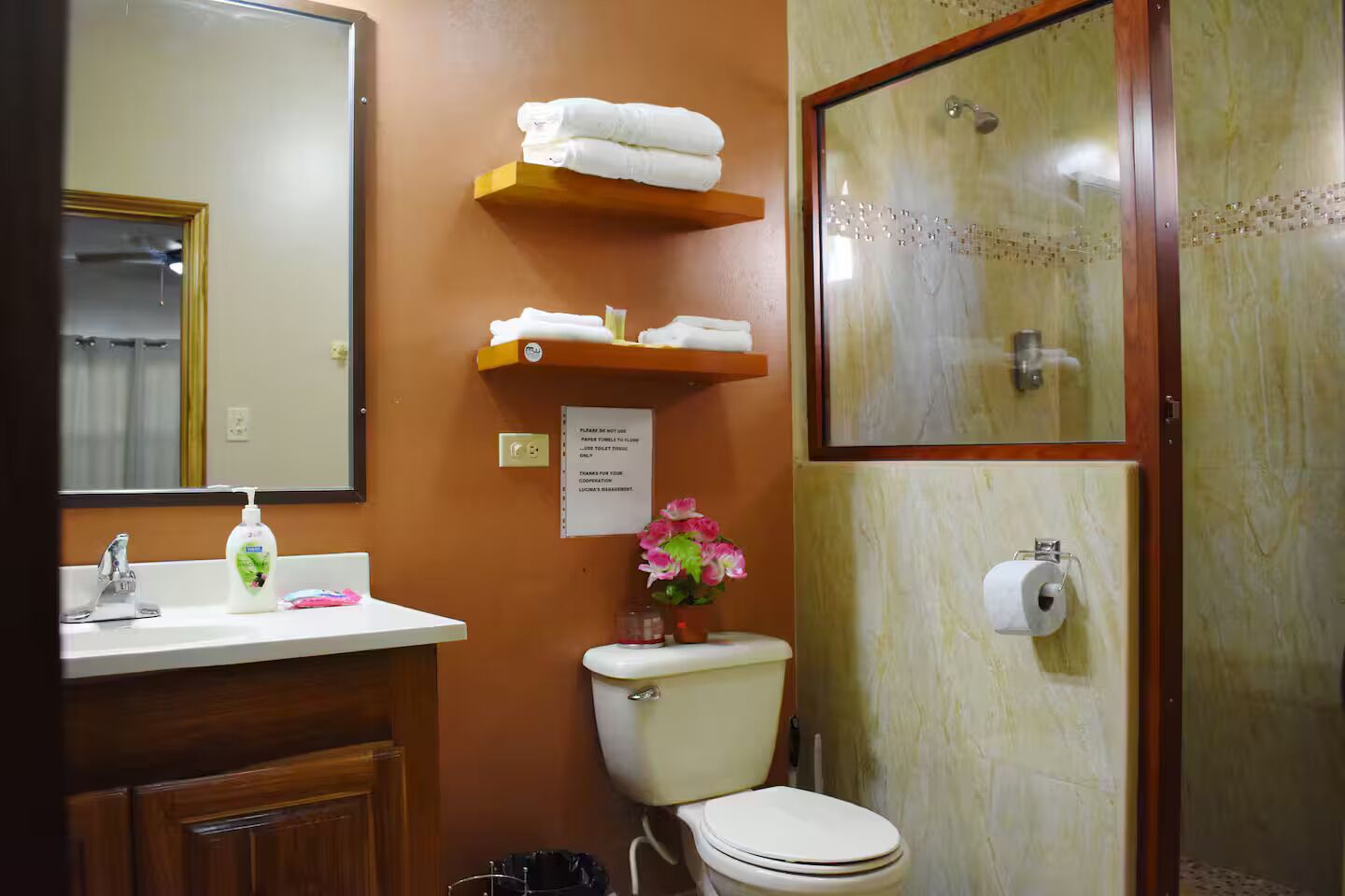A bathroom with a sink, mirror, toilet, and shower.