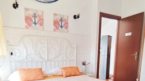 Ein Schlafzimmer mit Bett, Hängematte, weißem Kopfteil und einer Tür.
