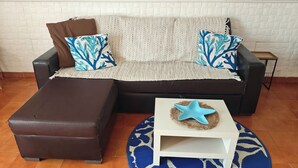 Ein modulares Sofa mit gemusterten Kissen, ein passendes Ottomanen und ein kleiner weißer Beistelltisch mit Sterndekoration.
