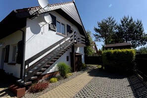 A two-story house with a wooden staircase, satellite dish, and a paved driveway. - Holiday Apartment for 4 People, Rowy (Ustka)