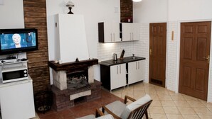 Een moderne keuken met witte kastjes, een open haard en een televisie.