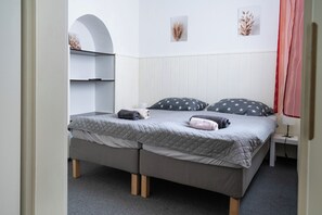 Un dormitorio con una cama, dos mesitas de noche, un armario y una puerta.