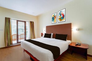 Habitación de hotel con una cama grande, una mesita de noche, un teléfono en la pared y una ventana con cortinas.