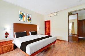 Habitación de hotel con una cama grande, cabecero de madera, mesitas de noche y una obra de arte en la pared.