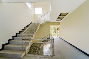A staircase with metal railings, carpeted steps, and a ceiling with recessed lighting. - Classic With Balcony Thiruvallam Lakeview (Thiruvananthapuram)
