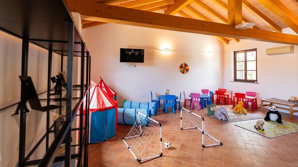 A room with a high ceiling, a television, a play area with a tent, and a window. - Tenuta Primero Grado Family Collection (Grado)