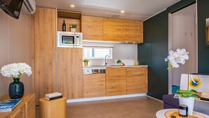 A compact kitchen with wooden cabinets, a microwave, and a small countertop. - Tenuta Primero Grado Family Collection (Grado)
