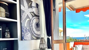 Ein modernes Wohnzimmer mit einem großen Spiegel, einem blauen Sessel und Meerblick.