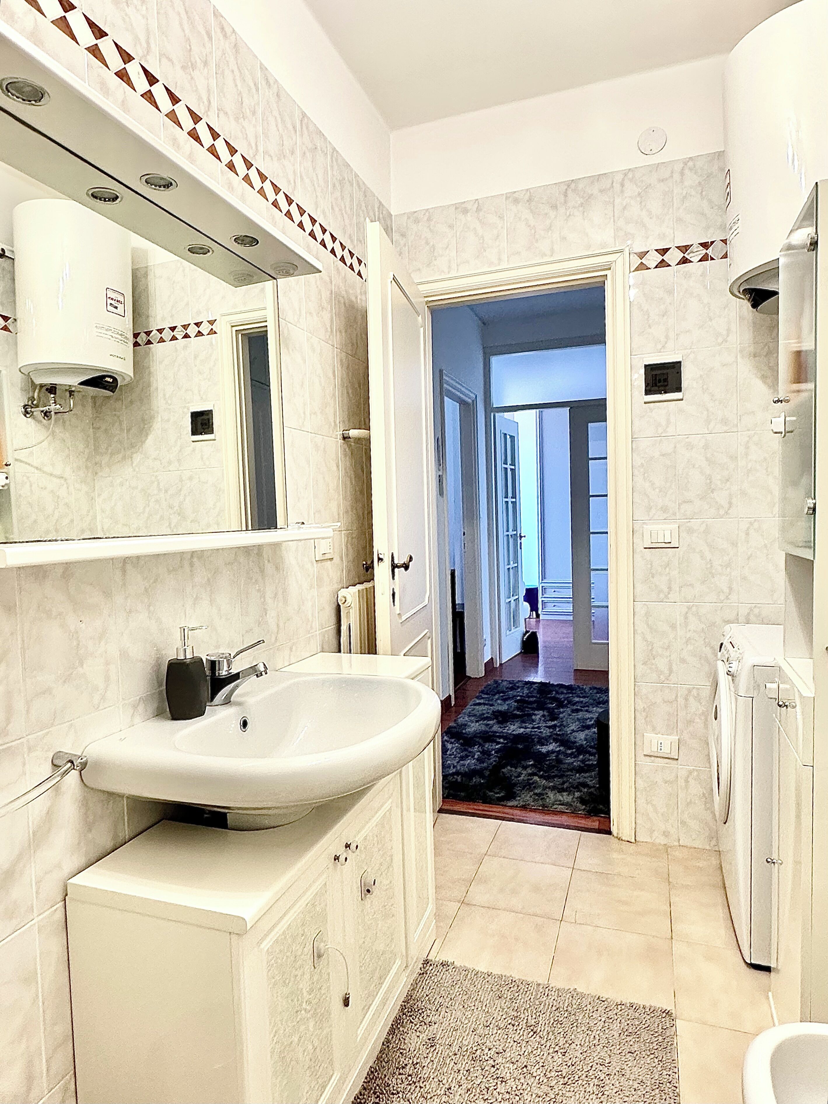 Un baño moderno con lavamanos, espejo y toallero.