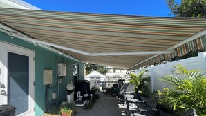 Un'area patio coperta con mobili da esterno, un sistema di filtraggio dell'acqua e piante in vaso.